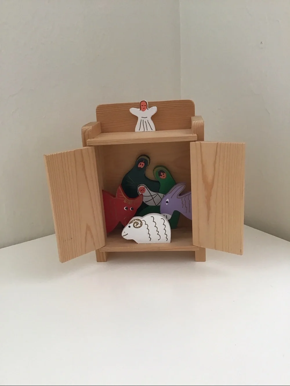 Handmade wooden cabinet holding a small wooden Nativity set